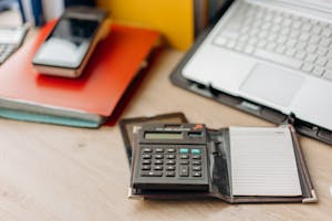 Organized workspace featuring a calculator, notepad, and laptop. Perfect for productivity themes.